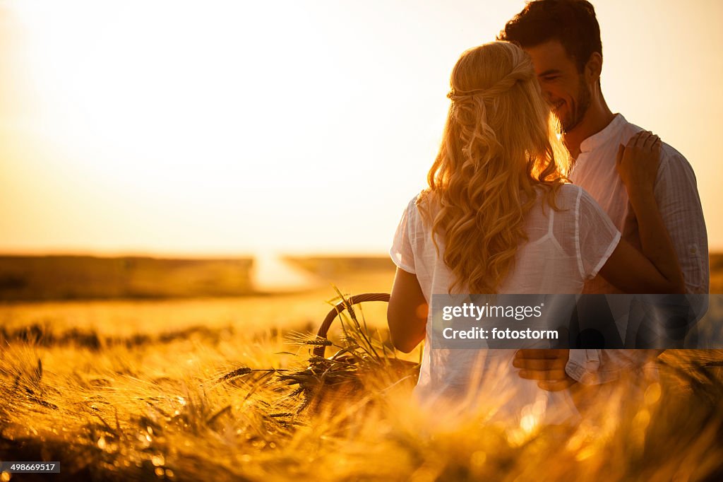 Pareja en el campo de trigo en puesta de sol