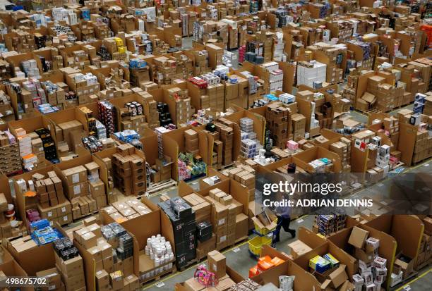 Workers walk along aisles of goods stored inside an Amazon.co.uk fulfillment centre in Hemel Hempstead, north of London, on November 25, 2015. Shops...