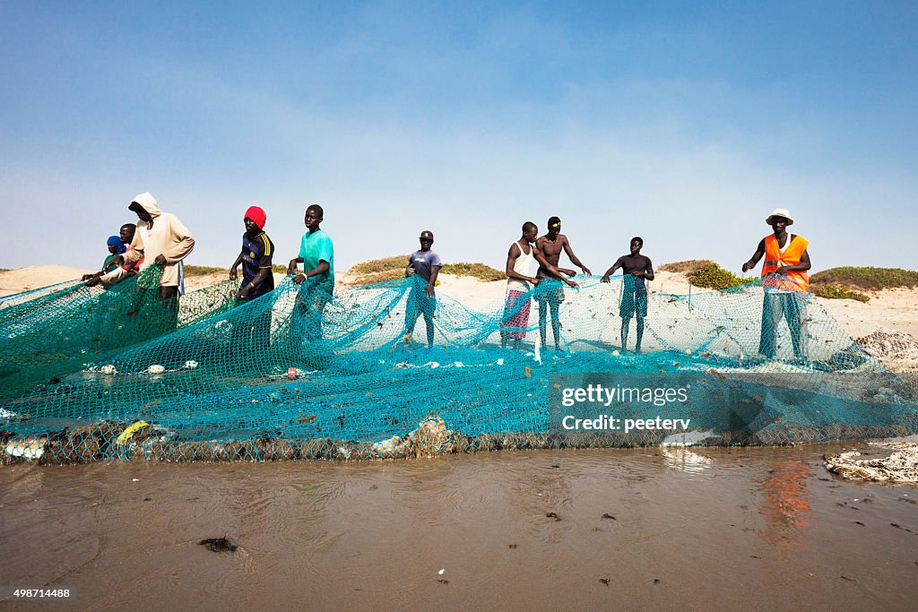 Los pescadores tiran de la red en la playa.