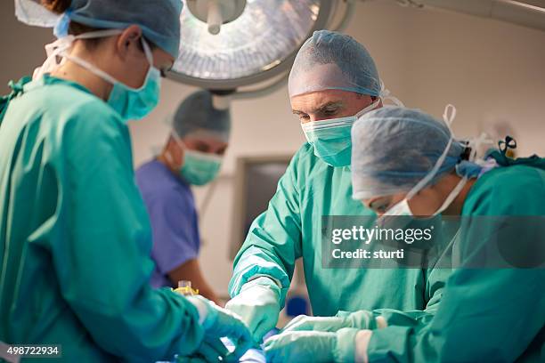 male and female surgeon during an operation - nhs stock pictures, royalty-free photos & images
