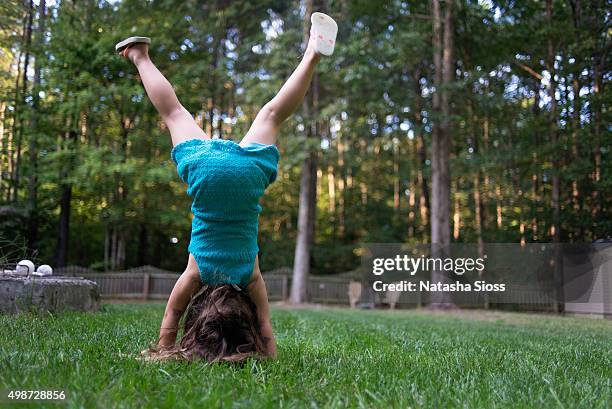 young girl in a blue dress doing handstands in the backyard - girl in dress doing handstand fotografías e imágenes de stock