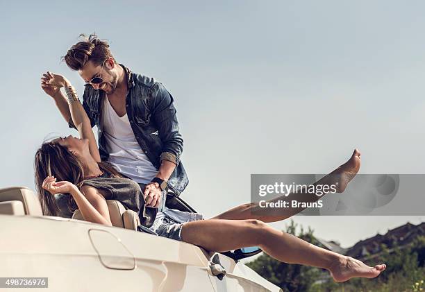 young playful couple having fun together on convertible car. - fashion model couple stock pictures, royalty-free photos & images