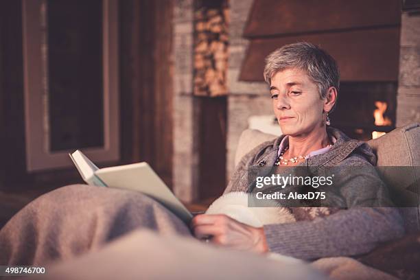 senior woman reading on sofa - covering gray hair stock pictures, royalty-free photos & images