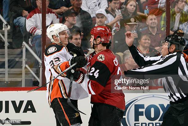 Jakob Silfverberg of the Anaheim Ducks and Kyle Chipchura of the Arizona Coyotes tangle as linesman Jay Sharrers skates in during the third period at...