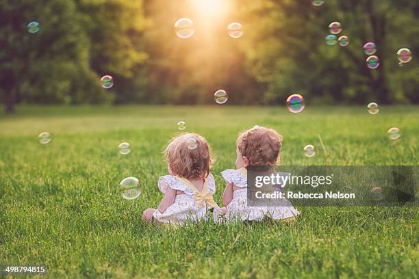 twin baby girls surrounded by bubbles - twin girls bildbanksfoton och bilder