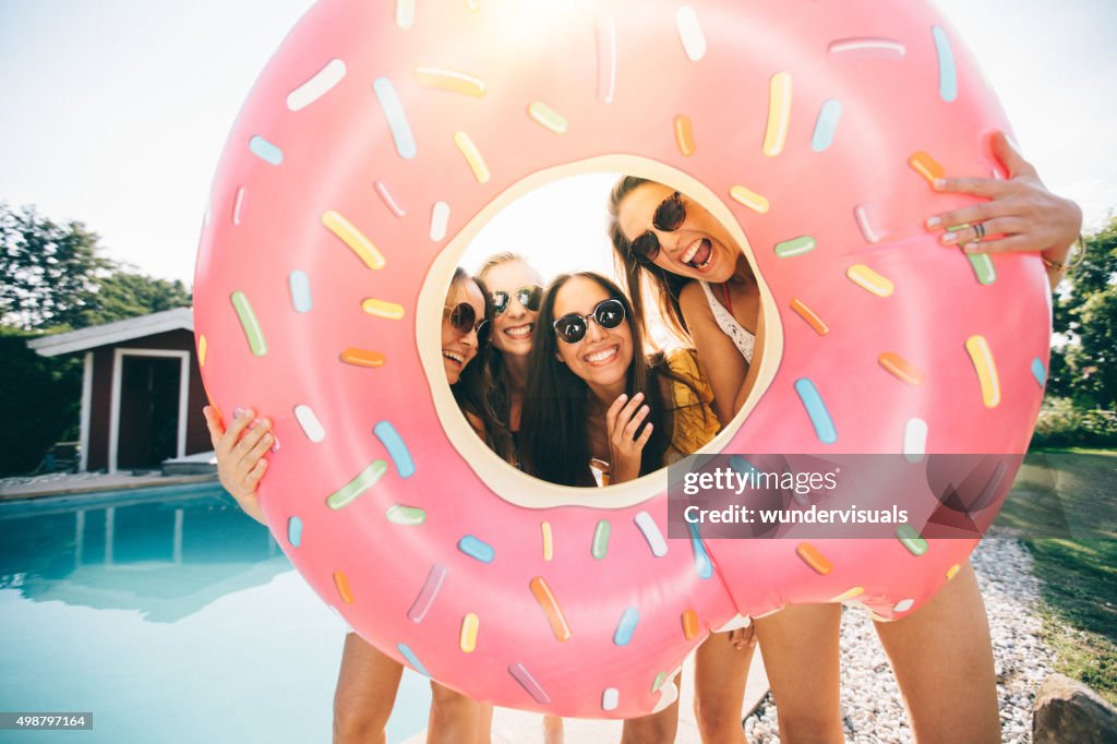 Girls laughing while holding a pool inflatable like a frame