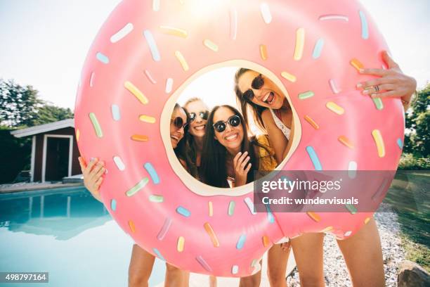 girls laughing while holding a pool inflatable like a frame - summer eyewear stock pictures, royalty-free photos & images