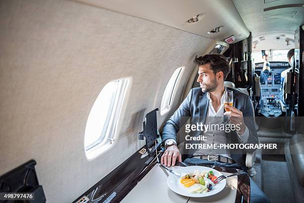 young businessman in private jet airplane - first class champagne stock pictures, royalty-free photos & images