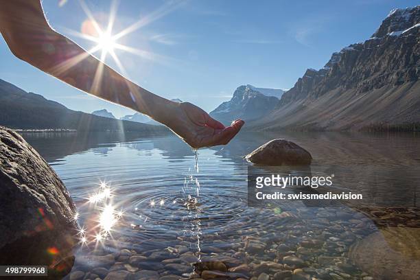 human hand cupped to catch the fresh water from lake - water stockfoto's en -beelden