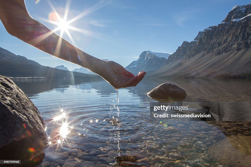 Human hand cupped to catch the fresh water from lake