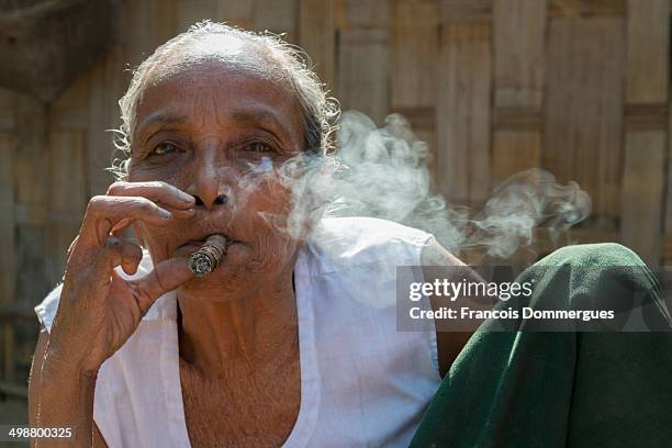 As in Myanmar, indigenous women smoke cheroots, local cigars made with strong tobacco. In a Marma village, an old lady enjoys her puffs in front of...
