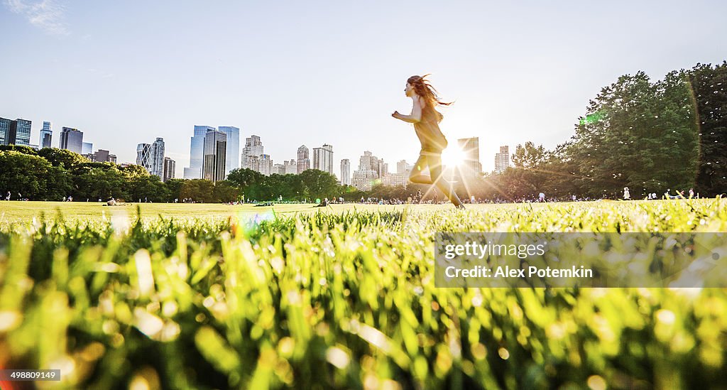 Girl runs in front of Manhattan skyline in Central Park