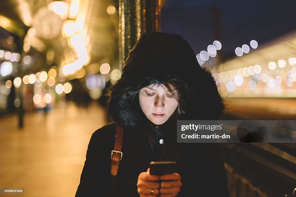 Donna presso la Stazione ferroviaria di SMS su smartphone