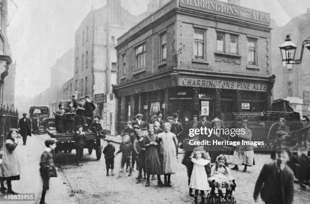 Busy East End street scene, London, 1912. View of a Charrington's pub at the junction of Crispin Street and Duval Street, near Spitalfields. Between...