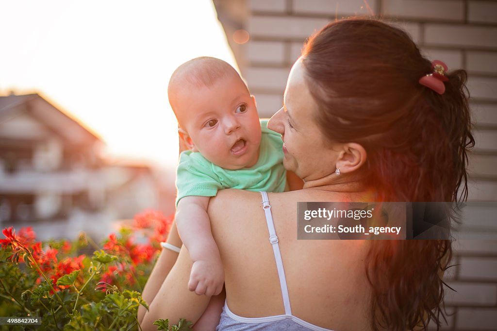 Mother holding baby against the sunset