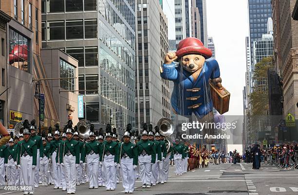People in colorful costumes carry cartoon characters' balloons during 89th Annual Macys Thanksgiving Day Parade in New York, USA on November 26, 2015.