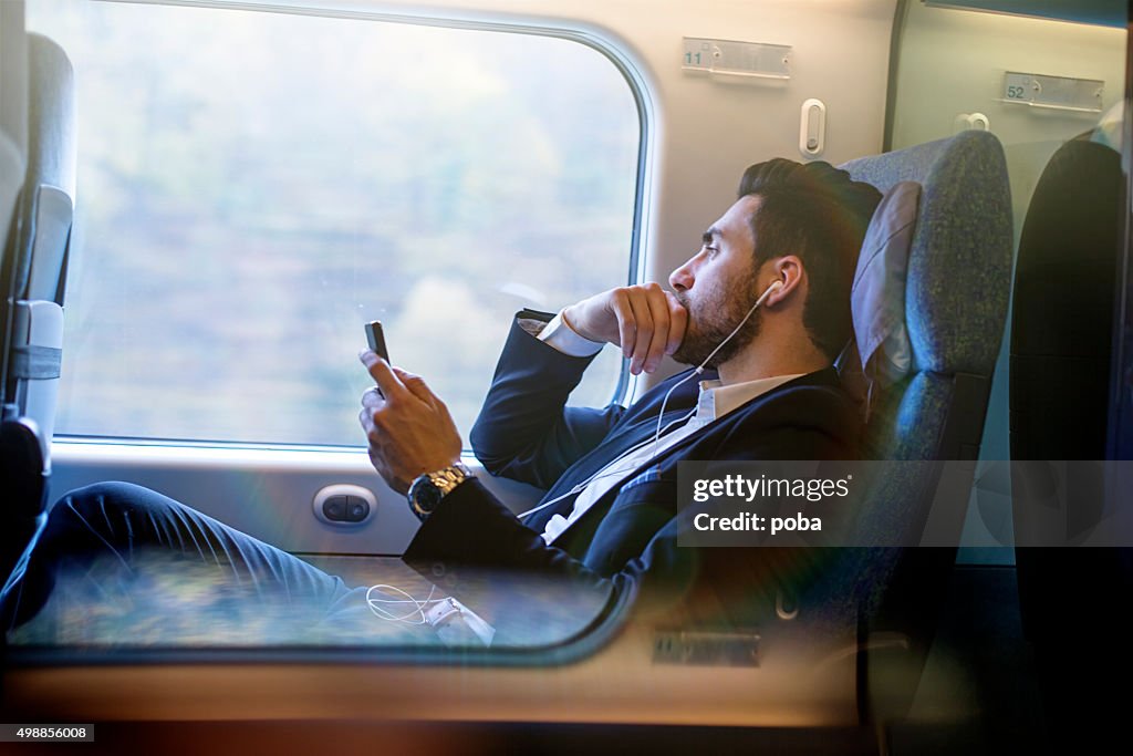 Bussinesman seating on a train beside window and working