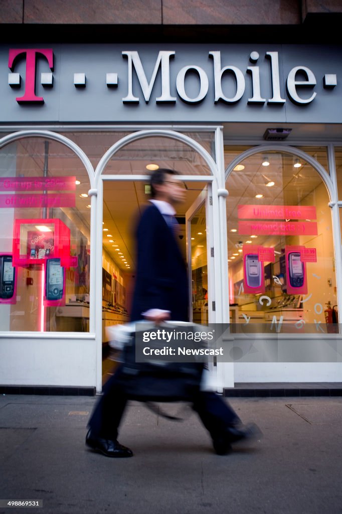 A businessman passes a T-Mobile store in the City