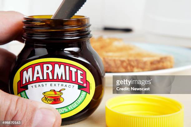 Man getting Marmite out of the jar with a knife.