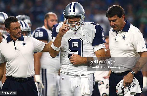 Tony Romo of the Dallas Cowboys is looked after by team officials after being sacked by the Carolina Panthers in the third quarter at AT&T Stadium on...