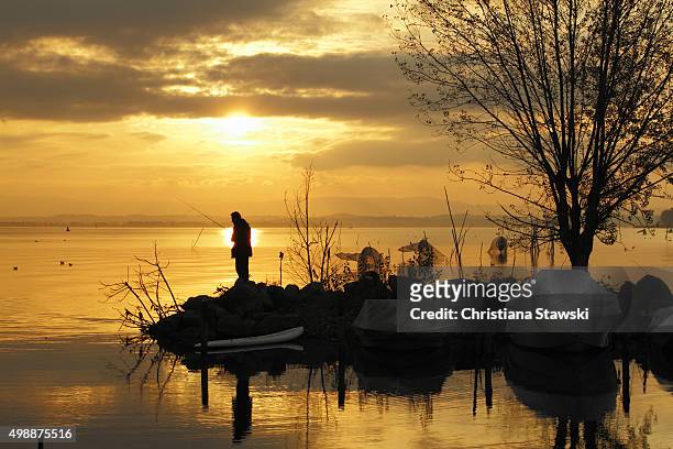 a man fishing on the shore of lake trasimeno - lac trasimeno photos et images de collection