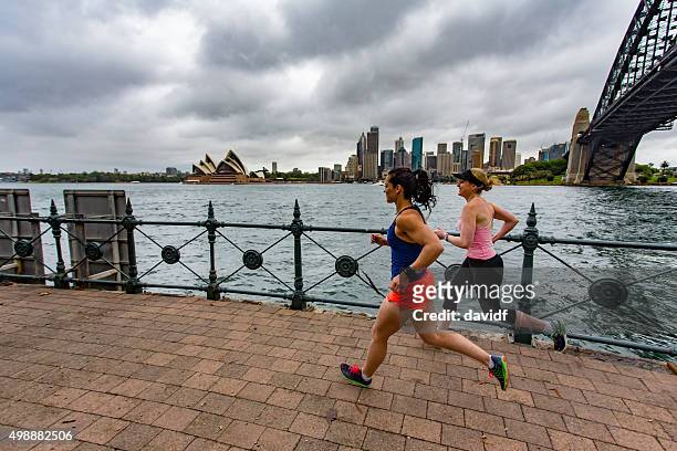 women running by sydney harbour - sydney opera house stockfoto's en -beelden