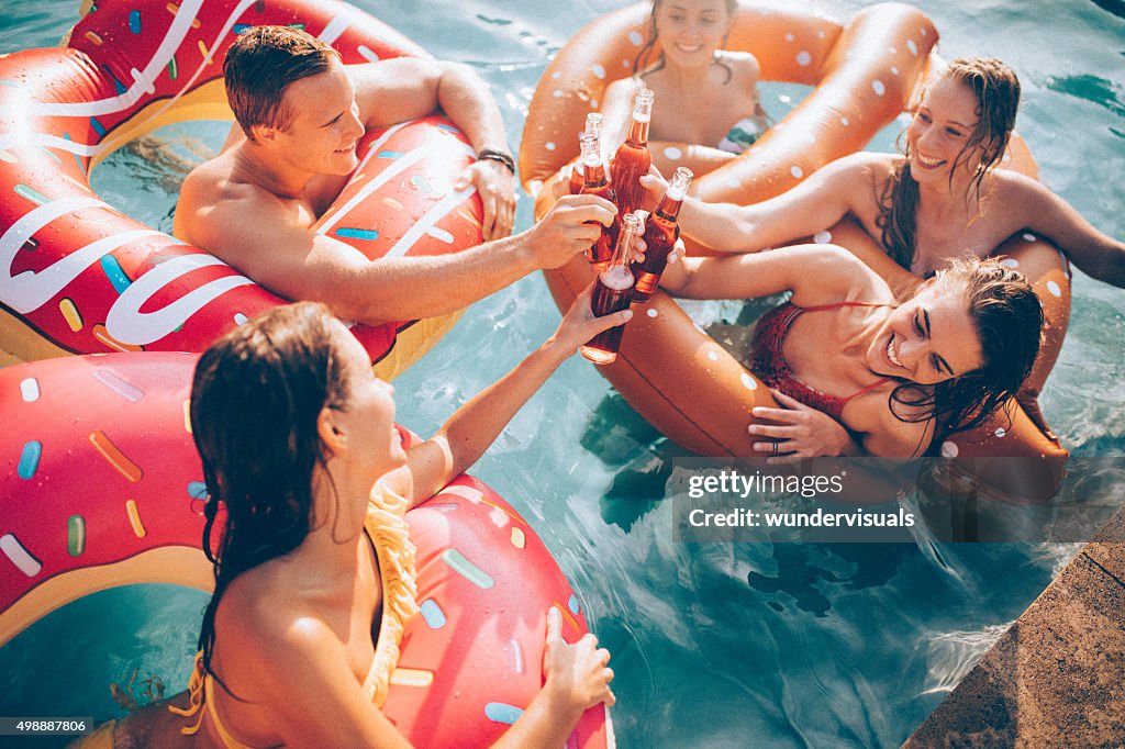 Amis de fête de l'été à la piscine avec boissons en bouteille