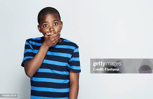 portrait of boy pulling funny face - mano tapando la boca fotografías e imágenes de stock