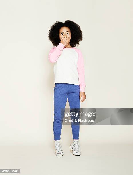 portrait of girl pulling funny face - mano tapando la boca fotografías e imágenes de stock