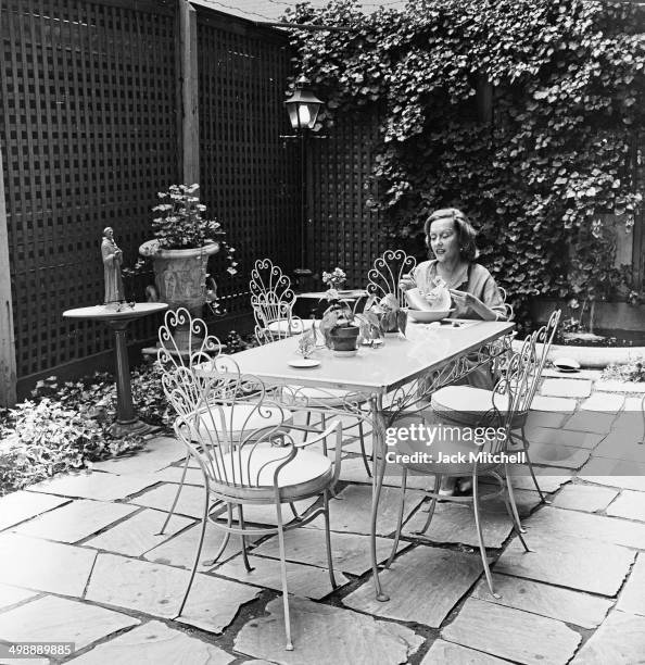 American actress Gloria Swanson eats a lunch of watermelon and iced tea on the private patio of her home, New York, New York, 1960.