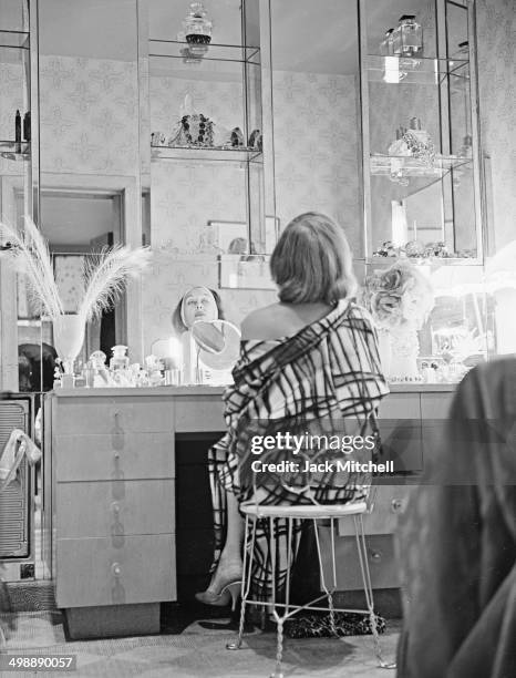 American actress Gloria Swanson applies her makeup in the dressing room of her home, New York, New York, 1962.