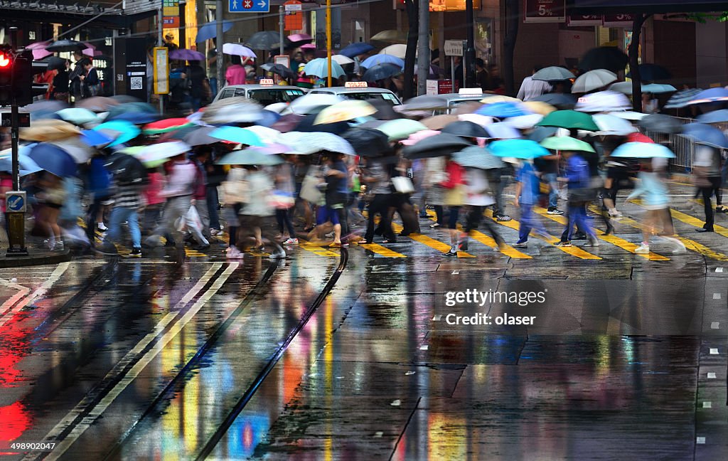 Mouvement flou de traversée de piétons dans la rue de Hong Kong à jets de pluie