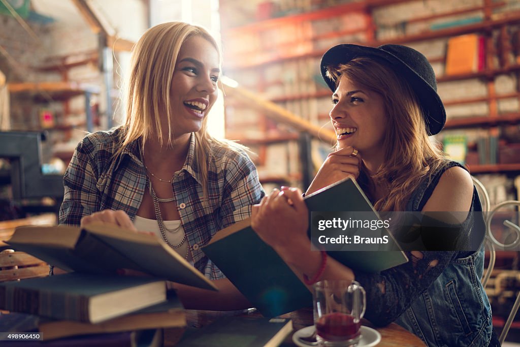 Cheerful female students talking to each other in a library.