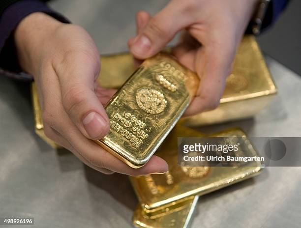 Gold bullions in the strong room of the pro aurum goldhouse in Munich. Hands with 1 kg and 12,5 kg gold bullions.