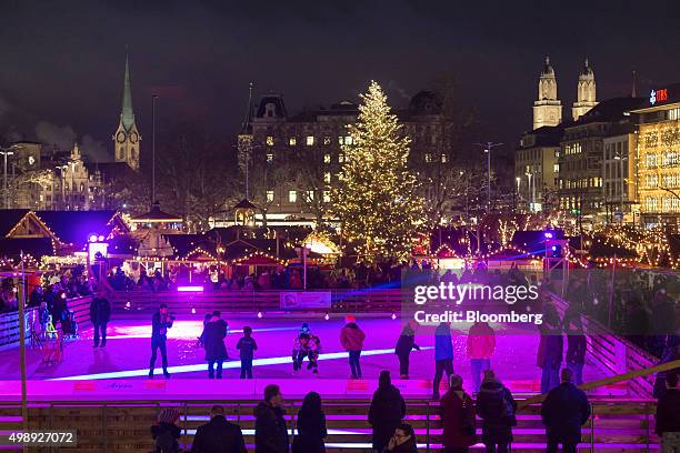 People skate on an ice rink as a Christmas tree and stalls stand illuminated at a Christmas market in front of the opera house in Zurich,...