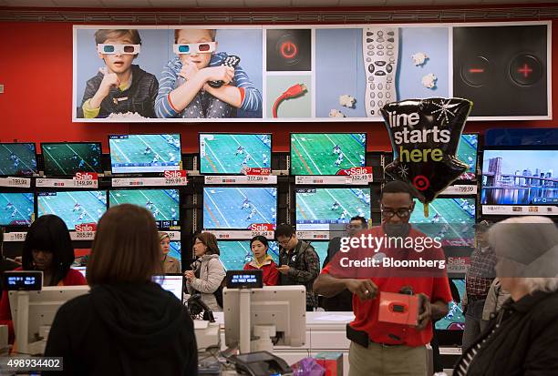 Customers stand in line in front of televisions displayed for sale at a Target Corp. Store in Jersey City, New Jersey, U.S., on Friday, Nov. 27,...