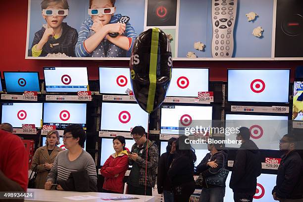 Customers stand in line in front of televisions displayed for sale at a Target Corp. Store in Jersey City, New Jersey, U.S., on Friday, Nov. 27,...