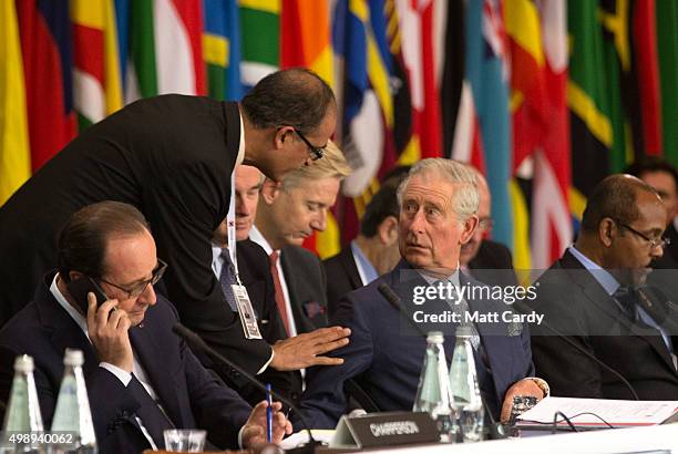 French President Francois Hollande takes a telephone call on his mobile as Prince Charles, Prince of Wales speaks with fellow delegates at a Special...