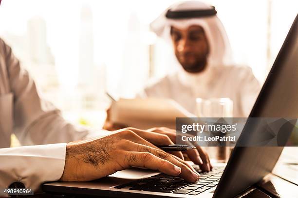 two emirates business men filling documents in a cafe - emirati at work stock pictures, royalty-free photos & images