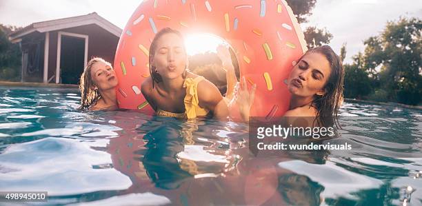 girls making kissing faces in a pool on summer afternoon - pool party stock pictures, royalty-free photos & images