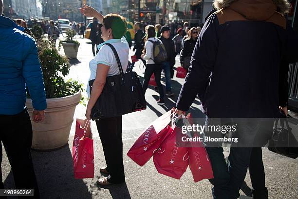 Pedestrians carry shopping bags on Black Friday through Herald Square in New York, U.S., on Friday, Nov. 27, 2015. In 2011, several big U.S....