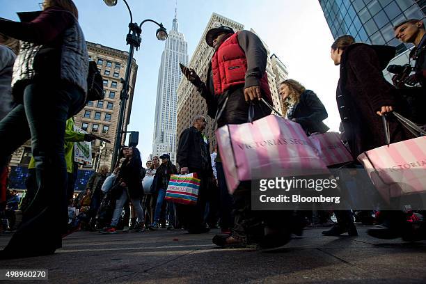 Pedestrians carry shopping bags on Black Friday through Herald Square in New York, U.S., on Friday, Nov. 27, 2015. In 2011, several big U.S....