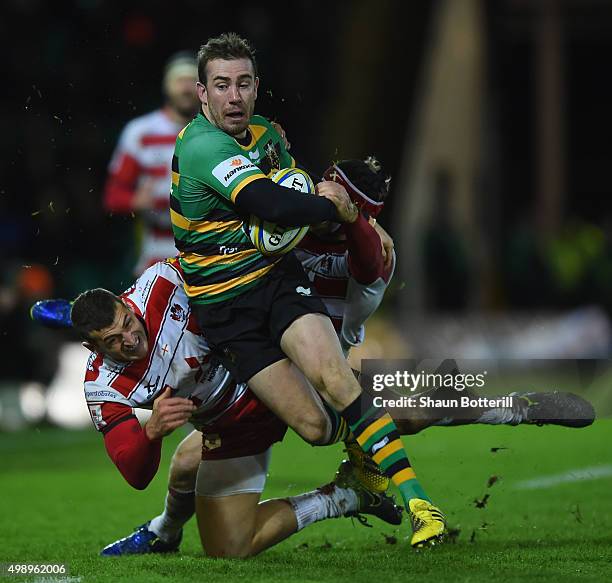 Hanrahan of Northampton Saints is tackled by Jonny May and Rob Cook of Gloucester Rugby during the Aviva Premiership match between Northampton Saints...