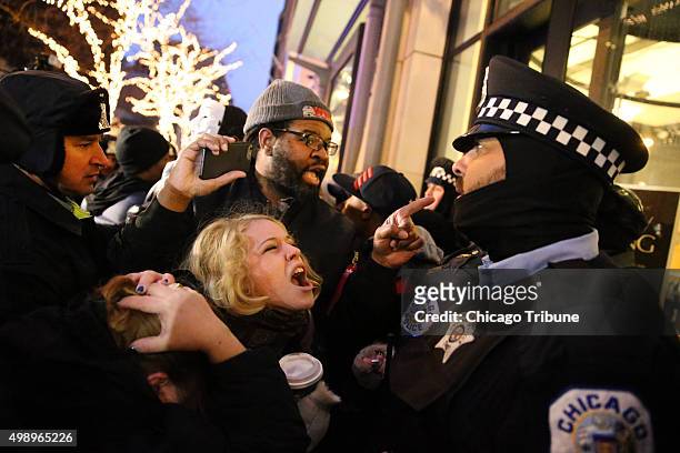 People scream at cops as they protest the shooting death of Laquan McDonald during a clash with Chicago police officers outside of a Banana Republic...