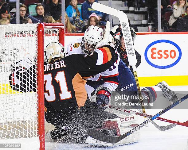 Mack Shields of the Calgary Hitmen gets knocked down by Taylor Cooper of the Regina Pats during a WHL game at Scotiabank Saddledome on November 27,...