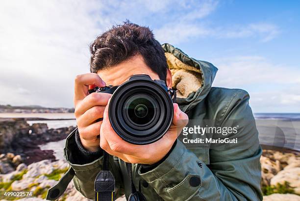 junger mann mit dslr-kamera - photographer stock-fotos und bilder