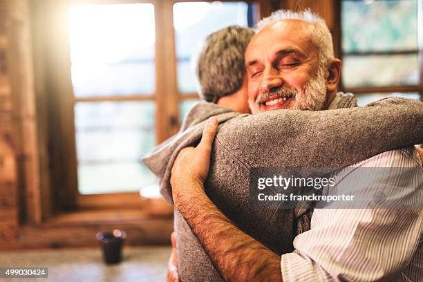 senior couple embracing passionate in the house - support concept - endosseren stockfoto's en -beelden