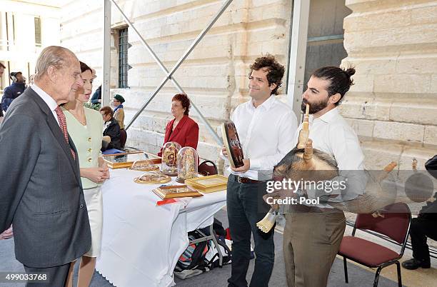 Prince Philip, Duke of Edinburgh smiles as he looks at Francesco Sultana playing the Zaqq, which is similar to the bagpipes and made from the carcass...