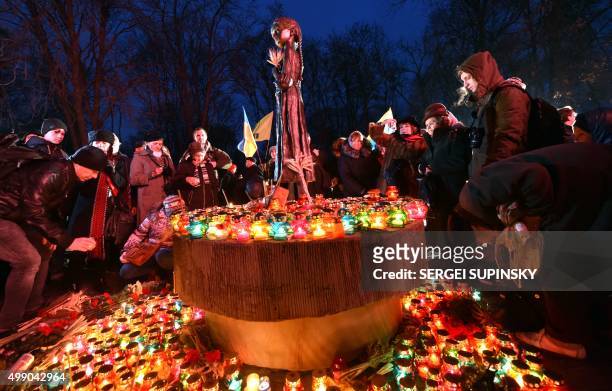 People place candles in memory of the victims of the Holodomor famine during a ceremony at the Holodomor memorial in Kiev on November 28, 2015. -...