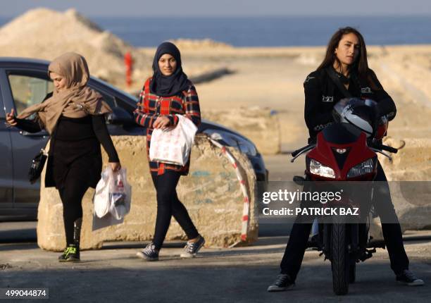 Veiled women walks pass Lebanese biker Grace Kassab in Beirut on November 28, 2015. Kassab, who is a photographer and a photo-editor for a local...